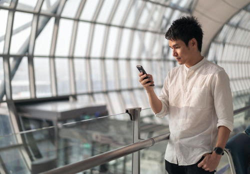 young man waiting for flight and using smart phone in airport